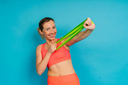 Self determined bodybuilder does exercises with rubber band, work on hands and legs. Sport concept.の写真素材