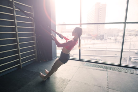 Beautiful muscular fit blonde woman exercising, building muscles in gymの写真素材