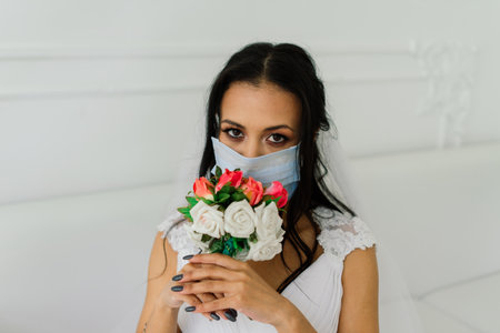 African American bride in dress, mask and in morning preparing for the wedding in hotel roomの写真素材