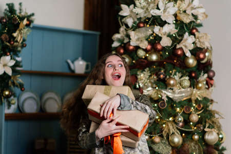 Beautiful young woman celebrating christmas at home, having fun opening presentsの写真素材