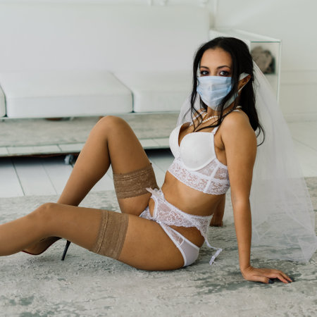 African American bride in lingerie, mask and in morning preparing for the wedding in hotel roomの写真素材