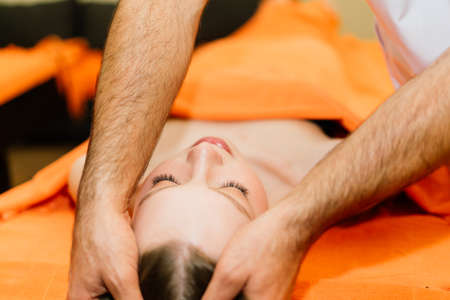 An attractive latin american woman lying down on a massage bed at spaの写真素材