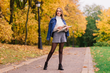 A young woman protecting from virus when walking in park. Autumn background.の写真素材