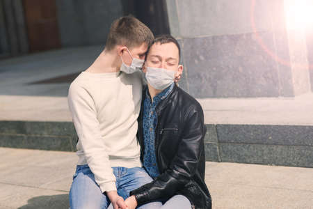Young gay couple wearing medical mask hugging at the city.の写真素材