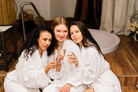 Three cute females in bath robes in the indoor pool. Women friends on vacation at Spaの写真素材