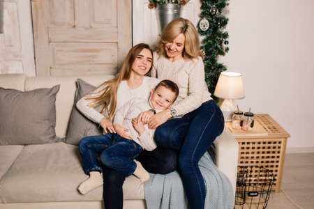 Happy family mother, daughter and son at a christmas tree at homeの写真素材