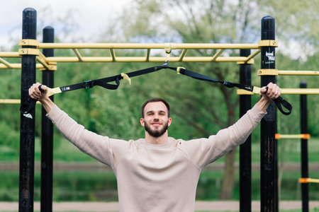 Caucasian sportsman pulling up wide grip hand on crossbar during street workout.
