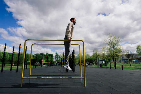 Caucasian sportsman pulling up wide grip hand on crossbar during street workout.の写真素材