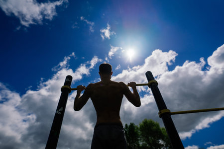 Caucasian sportsman pulling up wide grip hand on crossbar during street workout.