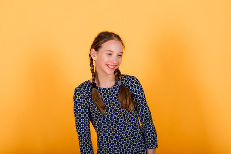 Pretty teenager girl smiling on camera looking cheerful on a yellow background. Positive emotionsの写真素材