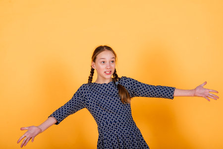 Pretty teenager girl smiling on camera looking cheerful on a yellow background. Positive emotionsの写真素材