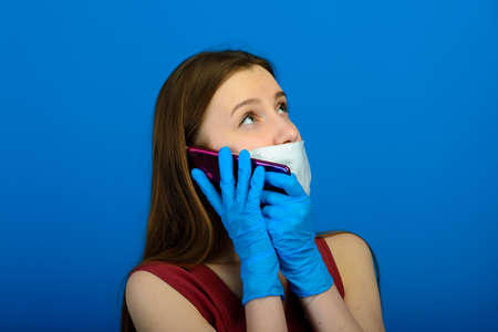 Female in a protective medical mask and blue gloves on blue background.の写真素材