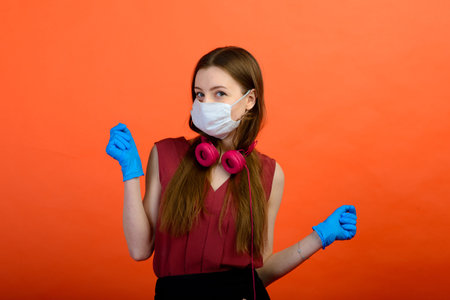 Female in a protective medical mask and blue gloves on red background.