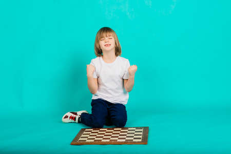 Boy holds a chessboard in his hands and looks at it, posing emotionalの写真素材