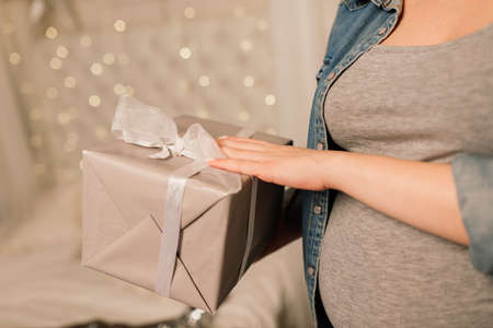 Close up of happy smiling pregnant woman touching her belly over a christmas tree backgroundの写真素材