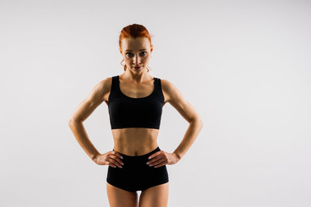 Seductive young redhead woman in bikini isolated on black, white background
