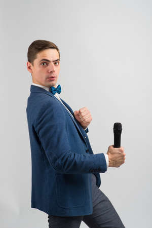 The entertainer. Young elegant talking man holding microphone, Isolated in a studio.の写真素材