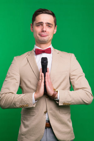 Portrait of male announcer holding microphone, isolated on green, white background