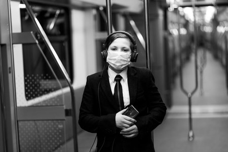 A boy in medical mask is sad at the train window, a child is traveling alone.の写真素材