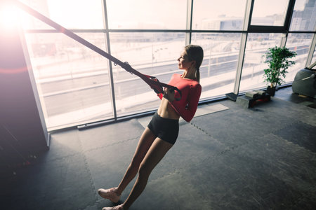 Sporty woman in a gym, dumbbells, barbell, smiling and fitnessの写真素材