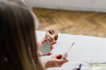 Beautiful lady doing make up and hair in bedroom. Attractive young female with pretty long hairの写真素材