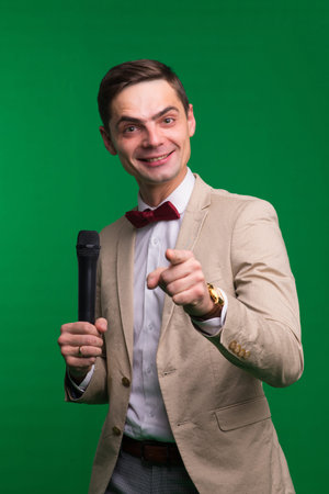 Portrait of professional male reporter holding microphone, isolated on white and green background