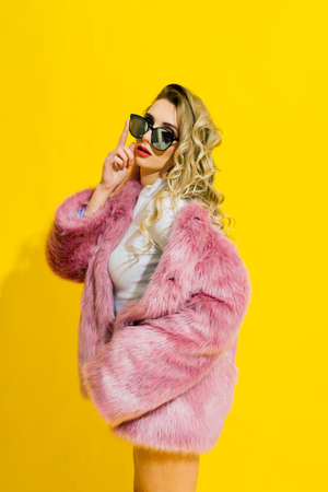 Gorgeous young woman posing in a luxurious fur coat and bodysuit. Fashion, beauty. Studio shot.の写真素材
