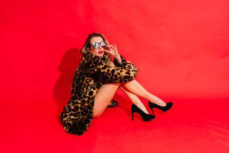 Gorgeous young woman posing in a luxurious fur coat and bodysuit. Fashion, beauty. Studio shot.