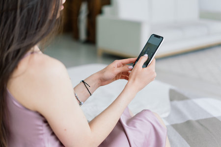 Cropped view of female hands holding smart phone. Woman with cell phone at home. Selective focusの写真素材