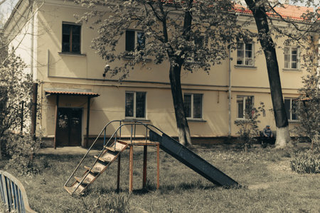 The old childrens slide stands on the playground tightened by fog aloone. Yellow paint peeled off.の写真素材