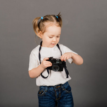 Child with camera. Little girl photographing in a studio backgroundの写真素材