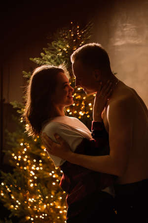 Young guy kissing lovely girlfriend feeling happiness while celebrating winter holidays togetherの写真素材