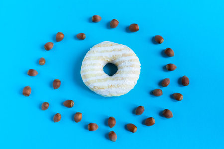 Donut with hazelnuts on a blue background, close up