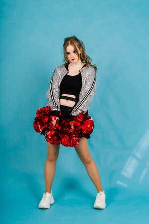 Beautiful young adult cheerleader female, studio red and blue backgrounds