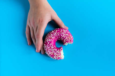 Hand holding half eaten sweet pink donut isolated. Half eaten donut isolated.の写真素材