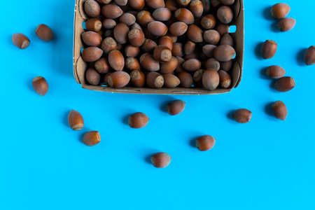 Box with hazelnuts over stone table, a blue background flatlayの写真素材