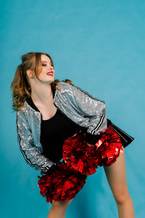 Young lady cheerleader posing in a studio, isolated on red and blue