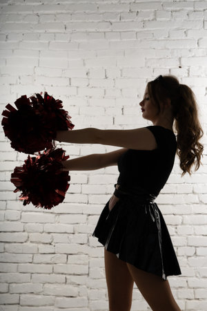 Young lady cheerleader posing in a studio, isolated on red and blue