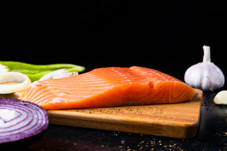 Salted fish salmon with pepper and onions on black plate. Top view. Free space for your text.