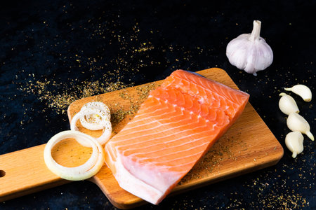 Salted fish salmon with pepper and onions on black plate. Top view. Free space for your text.