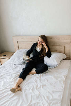 View of woman lying on a sofa and reading book at homeの写真素材