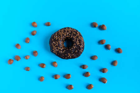 Donut with hazelnuts on a blue background, close upの写真素材