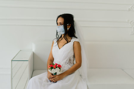 African American bride in dress, mask and in morning preparing for the wedding in hotel roomの写真素材