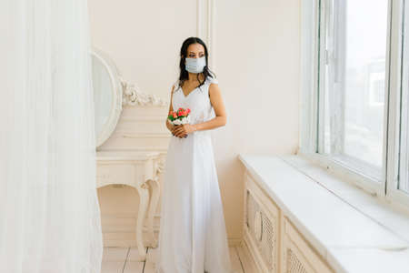 African American bride in dress, mask and in morning preparing for the wedding in hotel roomの写真素材