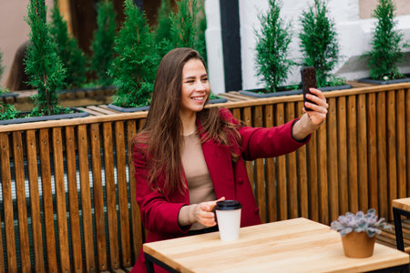 Happy woman at an outdoors cafe drinking and smiling