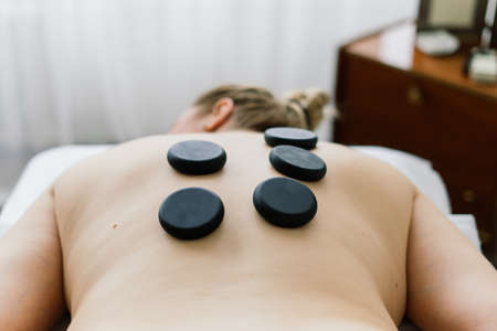 Plump woman getting hot stones arm massage in a spa salon. Therapy, wellness and relaxation conceptの写真素材