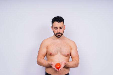 Full isolated studio picture from a young naked man with underwear and tomato