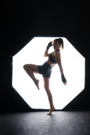 Strong sportswoman in boxing gloves prepared high kick. Isolated on white, red, yellow backgroundの写真素材