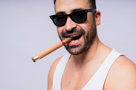 Close-up bearded caucasian man smoking a cigar. Wearing white shirt. Studio portraitの写真素材