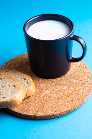 Breakfast bread and cup of milk on yellow and blue backgroundの写真素材